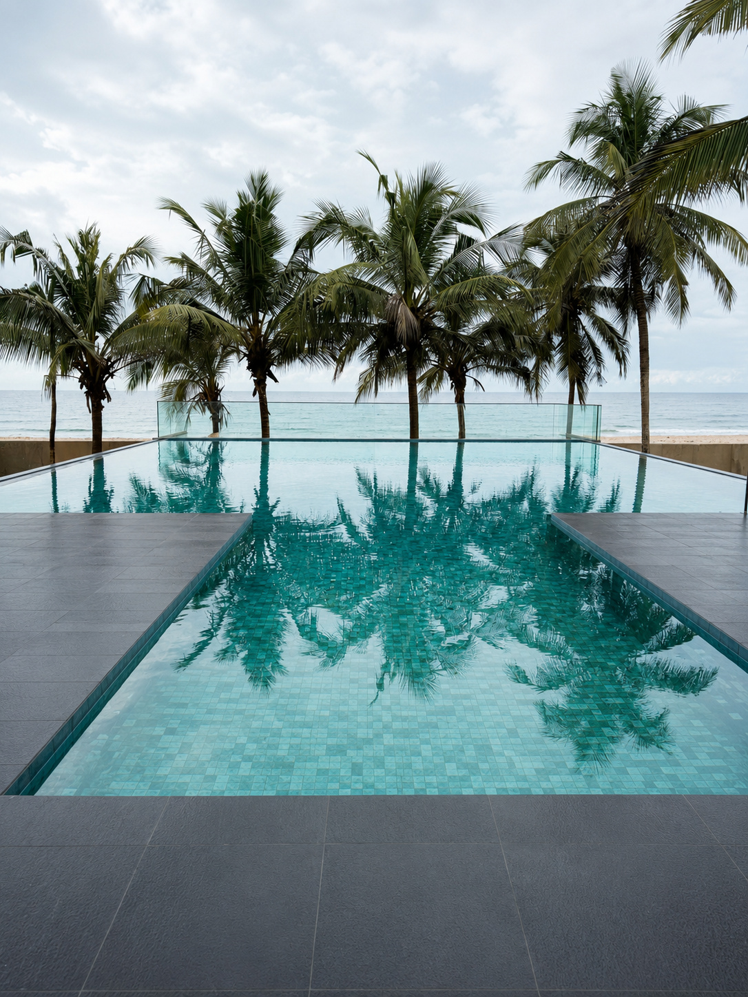 Ocean-edge infinity pool reflecting palm trees at Irele Beach Resort